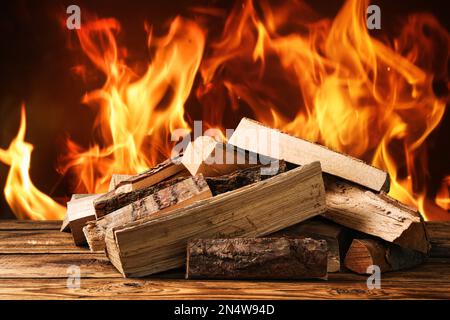 Trockenes Holz und brennendes Feuer im Hintergrund. Gemütliche Atmosphäre Stockfoto