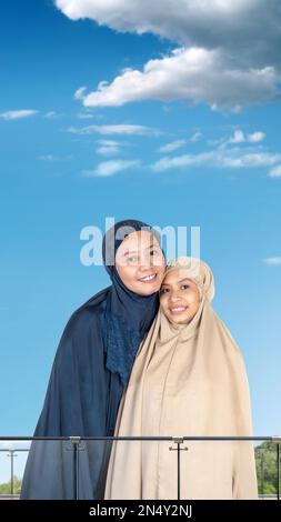 Asiatische muslimische Mutter und Tochter in einem Hidschab mit blauem Hintergrund Stockfoto