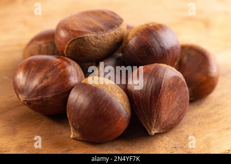 Ein Haufen rohe und ganze Kastanien auf einem Holztisch Stockfoto