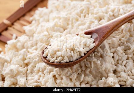 Reis-Koji in einem Sieb auf dem Tisch und einem Holzlöffel. Koji. Koji ist fermentierter Reis. Stockfoto