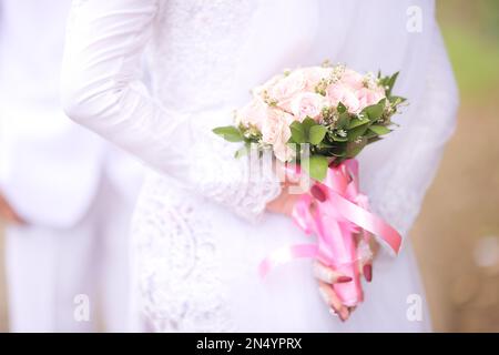 Die Braut hält den Strauß rosa Rosen mit Band Stockfoto