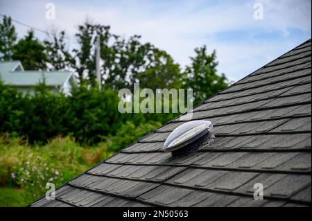 Kuppelförmiges Sonnenröhren-Oberlicht auf Asphalt-Schindeldach Stockfoto