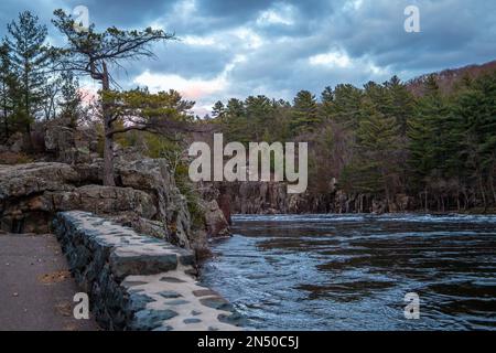 Dalles vom St. Croix River am Abend mit dramatischen Wolken über dem Fluss mit einer Steinmauer entlang einer Kante mit einer weißen Kiefer und dem Oppeln Stockfoto