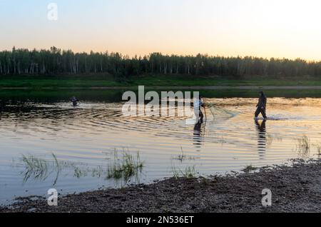 Zwei Männer Yakuts und ein anmutiges Mädchen in einem Schal, um in Watstiefel mit Fischnetz auf die Tierwelt im Fluss Vilyuy in einem traditionell fischenden Wald zu gehen Stockfoto