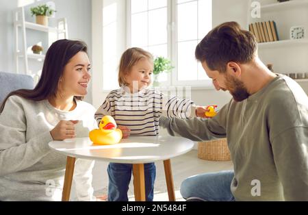 Das kleine Mädchen hat zu Hause Spaß beim Spielen mit ihren liebenden eltern. Stockfoto