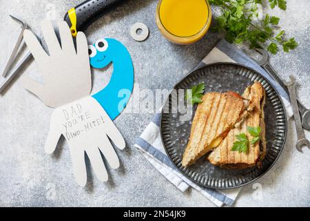 Alles gute zum Vatertag. Vatertag Karte Dinosaurier und Heimwerker Frühstück für Vater auf grauen Stein Tisch. Blick von oben. Stockfoto