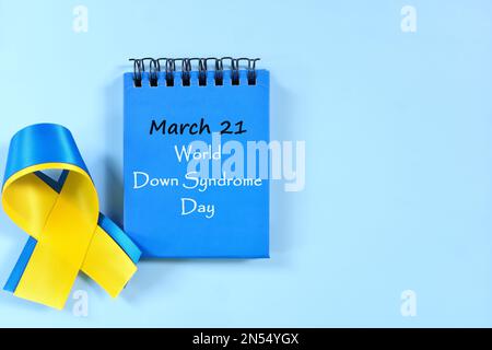 März 21 als Tag des Weltuntergangs-Syndroms-Datums auf blauem Schreibtischkalender mit gelbem und blauem Farbband. Festungskonzept. Stockfoto