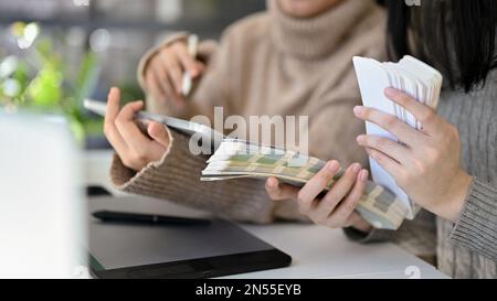 Zwei kreative asiatische Grafikdesignerinnen arbeiten im Büro zusammen und wählen Farben aus der Farbpalette für ihre Grafikarbeit. Zugeschnittenes Bild Stockfoto