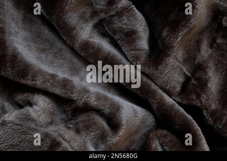 Hintergrund eines schwarzen Männermantels aus Schaffellack aus Kunstfell, Fellhintergrund Nahaufnahme Stockfoto