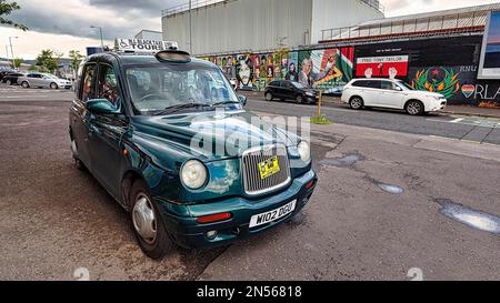 Taxi, Black Cab, geparkt vor einer Mauer mit Wandmalereien, Northern Ireland Black Taxi Tours, Belfast, Northern Ireland, Großbritannien Stockfoto
