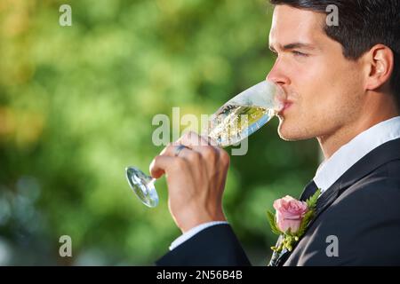 Genießen Sie einen ruhigen Drink an der Rezeption. Profilfoto eines jungen Bräutigams, der ein Glas Champagner trinkt. Stockfoto