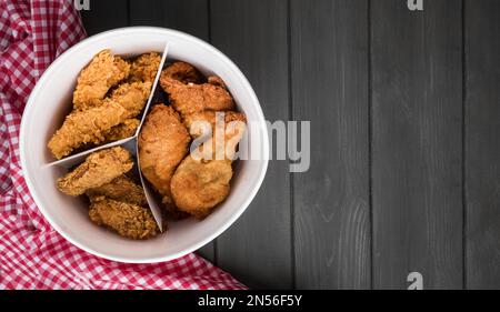 Blick von oben auf den Eimer mit gebratenem Hähnchen und einem Küchenhandtuch mit Kopierbereich. Auflösung und hochwertige Fotos Stockfoto