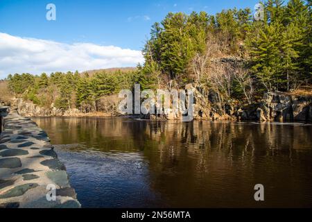 Wunderschöne Dalles of the St. Croix River mit zerklüfteten Klippen mit Kiefern entlang der Küste und einer Steinmauer am Fluss. Stockfoto