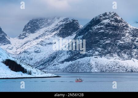 Fischerboot im Winter skandinavische Landschaft am Fjord, Meer, Berge, Schnee, Ramberg, Nordland, Lofoten, Norwegen Stockfoto