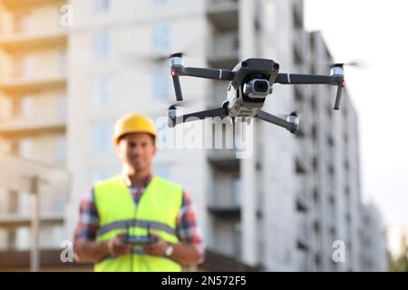 Bauarbeiter, die Drohne mit Fernsteuerung auf der Baustelle bedienen. Luftaufnahmen Stockfoto