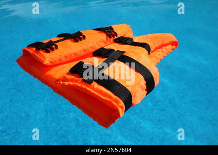 Im Swimmingpool schwimmende, orange Schwimmweste Stockfoto