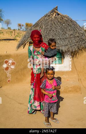 Farbenfroh gekleidete Wüstenbewohner, Schlammhütten in der Thar Wüste, Thar Wüste, Rajasthan, Indien Stockfoto