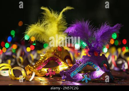 Wunderschöne Karnevalsmasken und Partydekor auf dem Tisch vor verschwommenem Licht Stockfoto