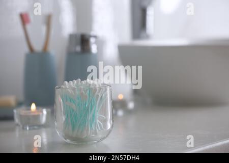 Glashalter mit Wattestäbchen auf weißer Arbeitsfläche im Badezimmer. Platz für Text Stockfoto