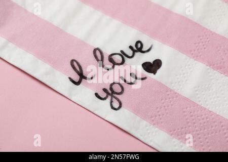 Serviette mit handgeschriebener Nachricht "Ich liebe dich" auf einem rosa Tisch Stockfoto