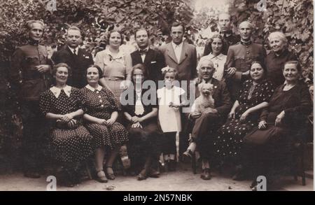 Vintage-Foto, das die Familie mit ihnen zeigt, die das Hündchen liebt / Vintage-Gedächtnis / gute alte Zeiten / Hündchen in der Hand halten / Hunde umarmen / Hund umarmen / Hund unter den Armen halten Stockfoto