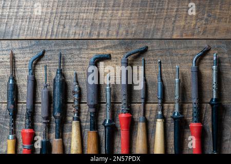 Viele alte Lötkolben auf Holzhintergrund, Nahaufnahme, Draufsicht, Kopierbereich Stockfoto