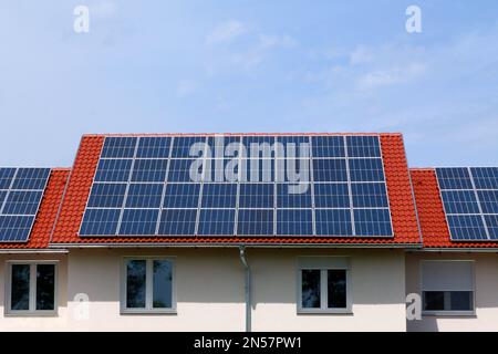 Solarpaneele für Photovoltaik-Sonnenkollektoren auf geneigtem Tonhausdach. Blauer Himmel und weiße Wolken. Alternative Energie. Umweltschutz. Außerhalb des Netzes Stockfoto