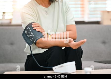 Blutdruck- und Herzfrequenzmessung bei Frauen mittleren Alters mit digitalem Tonometer. Altenpflege und Medizinisches Konzept Stockfoto