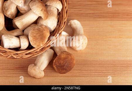 Rohe weiße Pilze im Korb auf einem Holztisch Stockfoto