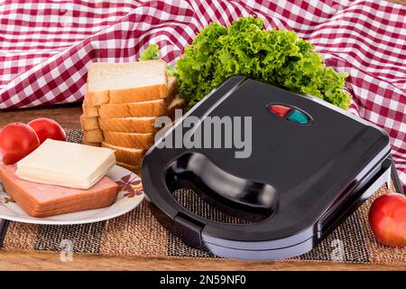 Schwarzer Sandwichmaker; Foto auf Holzhintergrund Stockfoto