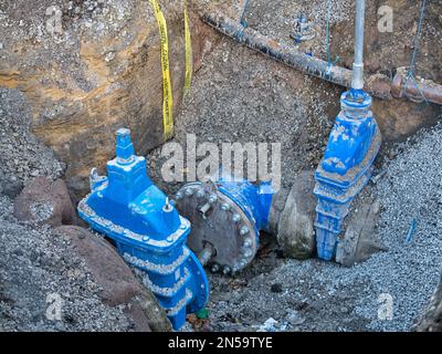 Absperrarmaturen in einem gegrabenen Graben auf einem Gehweg - Teil eines Wasserversorgungsnetzes in Großbritannien. Stockfoto