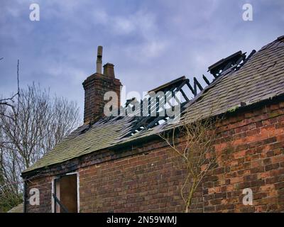 Das abgebrannte Dach eines verlassenen Bauernhauses in Flintshire, Nordwales, Großbritannien. Im Winter mit bedecktem Himmel aufgenommen. Stockfoto