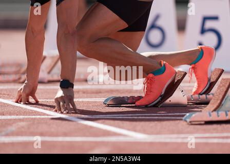 Ein Mann in einem Startblock auf einer Sportstrecke. Ein Sprinter in einem Track-and-Field-Rennen steht vor der Startlinie und wartet auf den Start Stockfoto