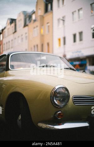 Ein alter Oldtimer steht auf einer Straße. Das gelbe Auto ist Retro und das Oldtimer sorgt für Nostalgie. Es ist eine Nahaufnahme. Stockfoto