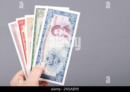 Altes chilenisches Geld - Escudos in der Hand auf grauem Hintergrund Stockfoto