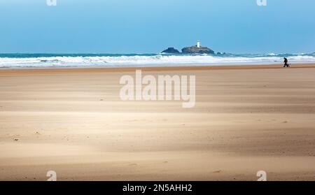 Hundefreunde an einem eiskalten, sehr windigen Tag im März. Aufgenommen am Upton Towans Beach in North Cornwall mit Blick auf den Godrevy Lighthouse Stockfoto