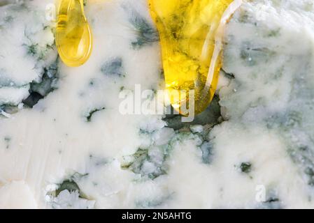 Makroaufnahme von Blaukäse Dorblu oder Gorgonzola mit Honig. Schließen. Lebensmittelstruktur. Italienische Vorspeise Stockfoto