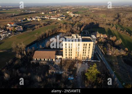 Februar 2023: Blick aus der Vogelperspektive auf ein verlassenes Gebäude mit künstlichem See in Cortina, Piacenza, Italien Stockfoto