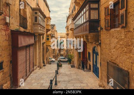 Alte mittelalterliche, enge Straße mit Balkonen auf alten Häusern in Valletta, Malta mit niemandem. Reiseziel in Europa Stockfoto