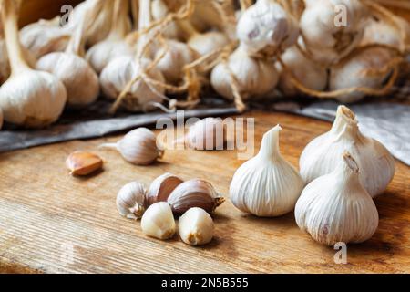 Hausgemachte Knoblauchknolle auf rustikalem Holztisch. Frische geschälte Knoblauchzehen. Stockfoto