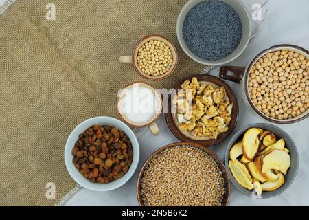 Verschiedene vegetarische Bio-Lebensmittel in Schüsseln. Weizen, Mohnsamen, Soja, Rosinen, Nüsse, Kaffee, Nudeln. Draufsicht. Speicherplatz kopieren. Stockfoto