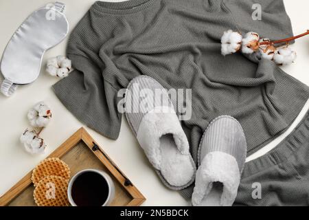 Flach liegend mit Hausschuhen und Schlafanzug auf beigefarbenem Hintergrund. Bequemes Heim-Outfit Stockfoto