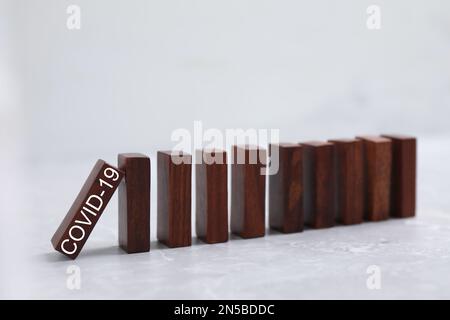 Herunterfallende Domino-Fliesen aus Holz auf einem grauen Marmortisch. Verbreitung des Coronavirus-Konzepts Stockfoto