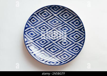 Handbemalte blaue Keramikschale mit Ziergegenständen im zentralasiatischen Stil auf weißem Hintergrund Stockfoto