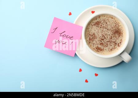 Papier mit Words I Love You, Kaffee und kleinen roten Herzen auf hellblauem Hintergrund, flach liegend. Platz für Text Stockfoto