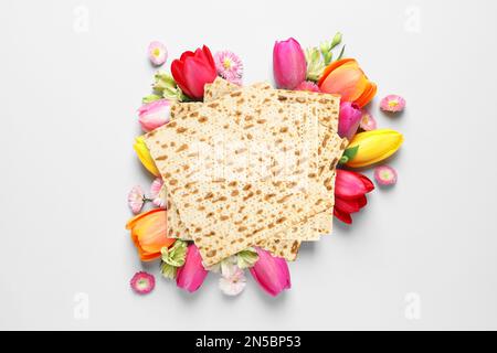 Leckere Matzen und Blumen auf hellem Hintergrund, flach liegend. Pessach-Feier Stockfoto