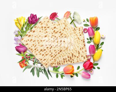 Leckere Matzen und Blumen auf weißem Hintergrund, Draufsicht. Pessach-Feier Stockfoto