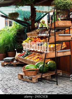 Obststand auf einem Straßenmarkt draußen mit organischen Wassermelonen, Orangen, Zitronen in Holzkisten kleine Unternehmen vegane gesunde Lebensmittel Stockfoto