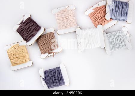 Die Schäume von Baumwollfäden verschiedener Farben liegen auf einem Stapel auf weißem Hintergrund Stockfoto