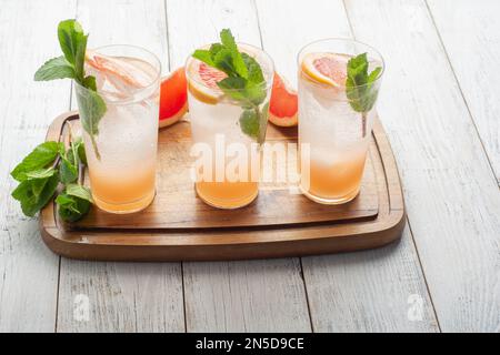 Sommerliche erfrischende Fruchtgetränke mit Eis auf einem grauen Küchenbrett Stockfoto